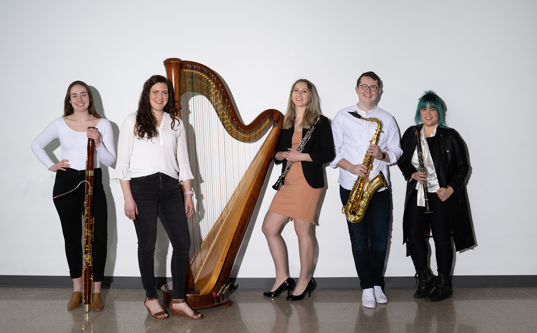 the blank experiment group photo. They are standing in front of a white wall and smiling at eachother while holding their instruments